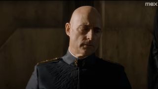 Emperor Javicco Corrino, played by Mark Strong, in Dune: Prophecy. Close up of a bald man wearing a dark gray military-style jacket