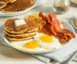 Crispy bacon next to American pancakes and fried eggs