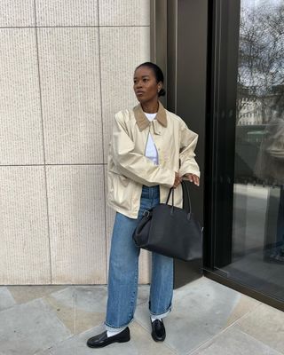 @nlmarilyn looks effortlessly cool in a t-shirt, barn jacket, ankle grazer jeans, socks, and loafers.