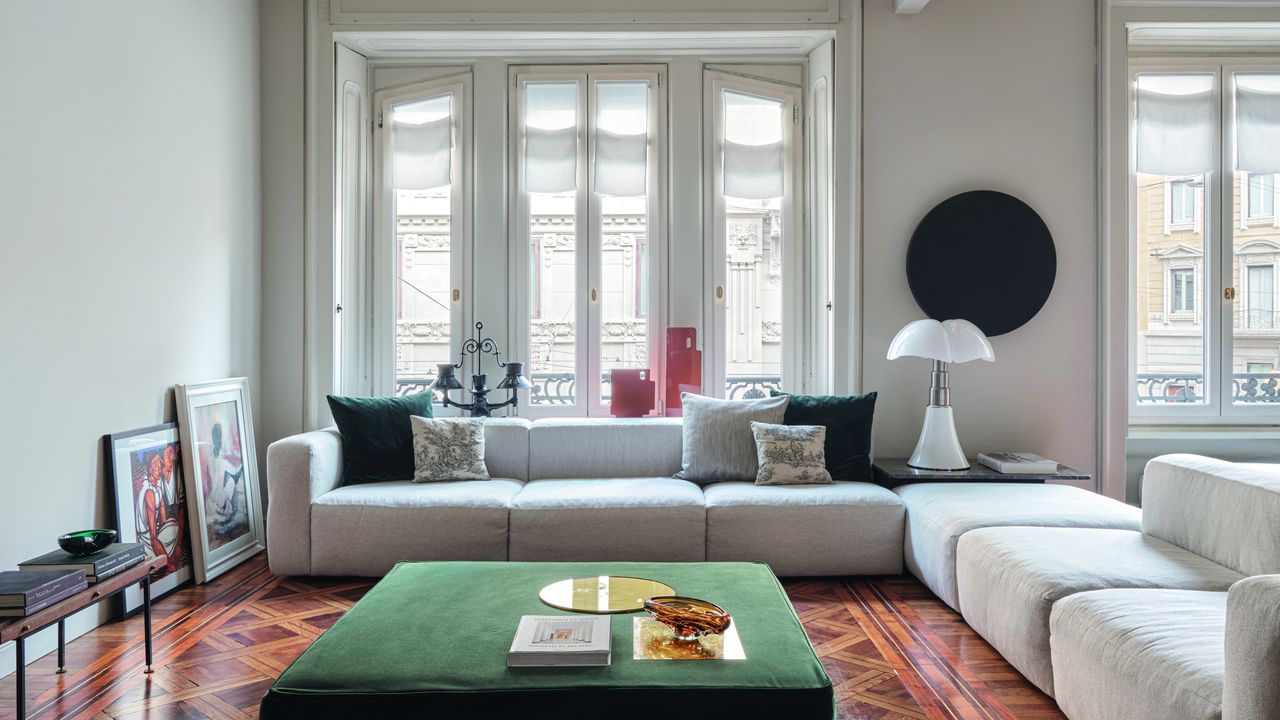 White living room with polished wood floor, white modular corner sofa and green velvet upholstered coffee table