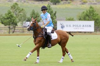 Prince Harry riding a polo horse across a field