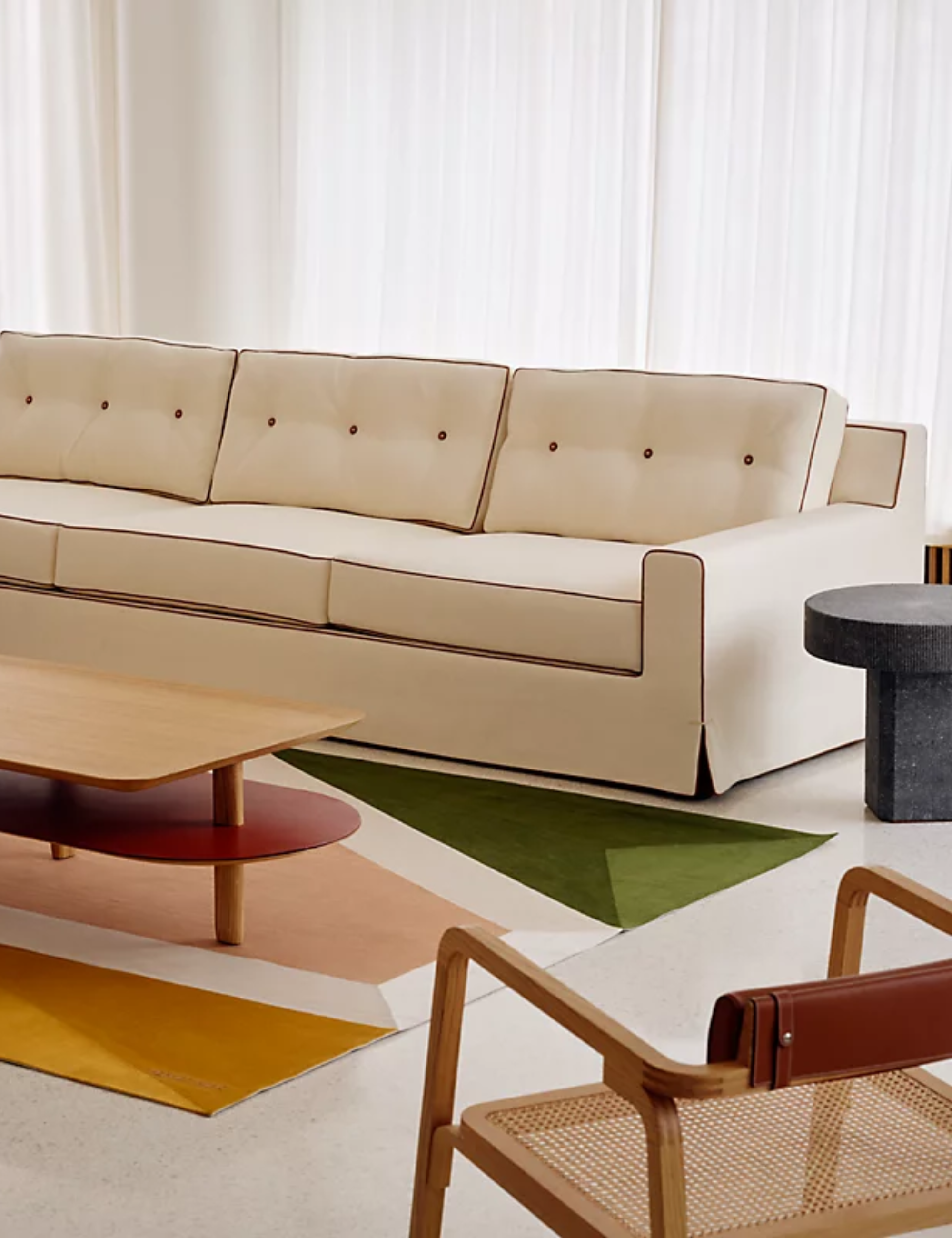 Herm&amp;egrave;s sofa, accent chair, coffee table, and colorful geometric rug styled inside of an airy living room