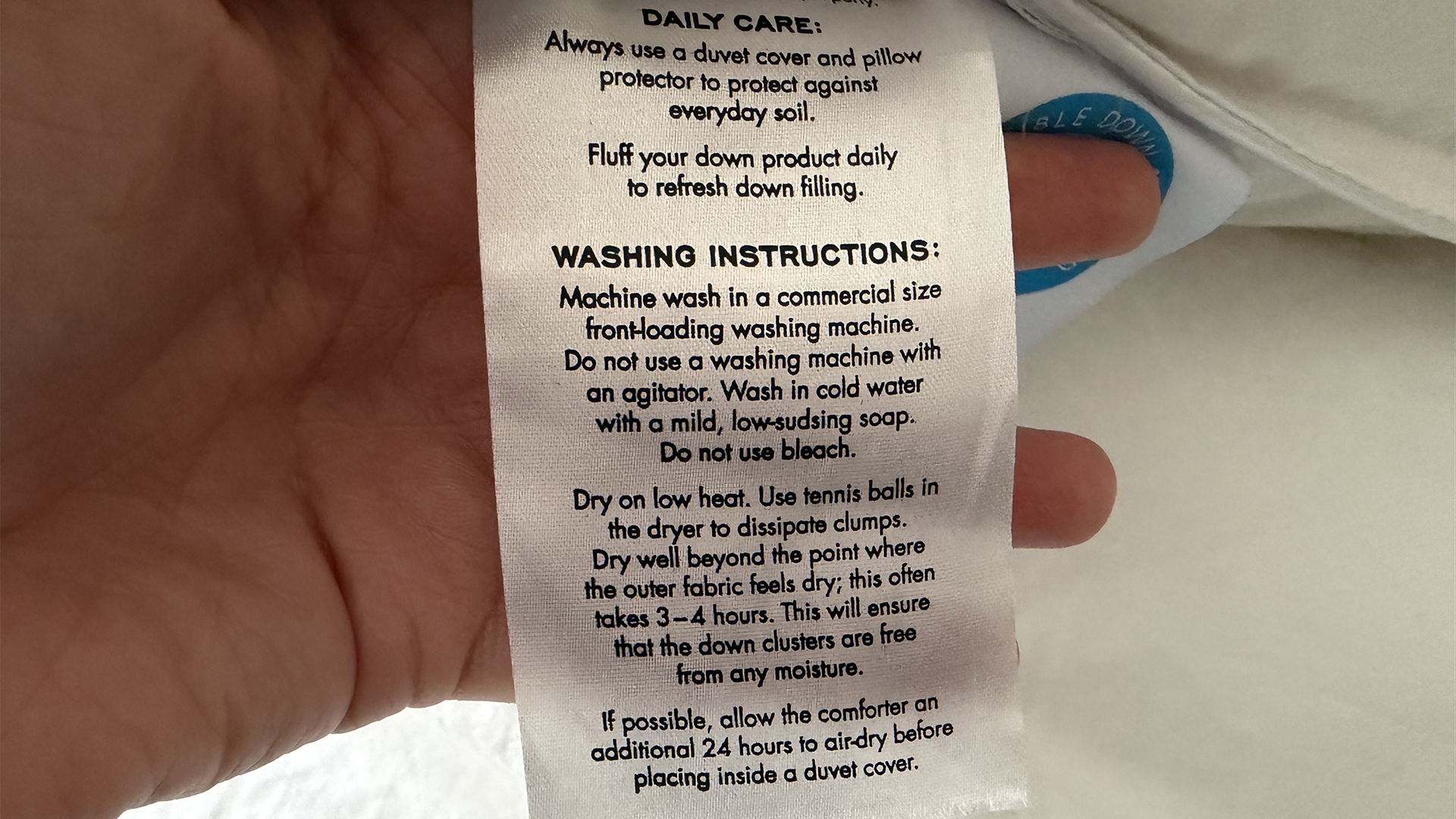 A close up of the care instruction label for the Downright Mackenza WD pillow. It advices washing in cold water with a mild soap and drying for several hours