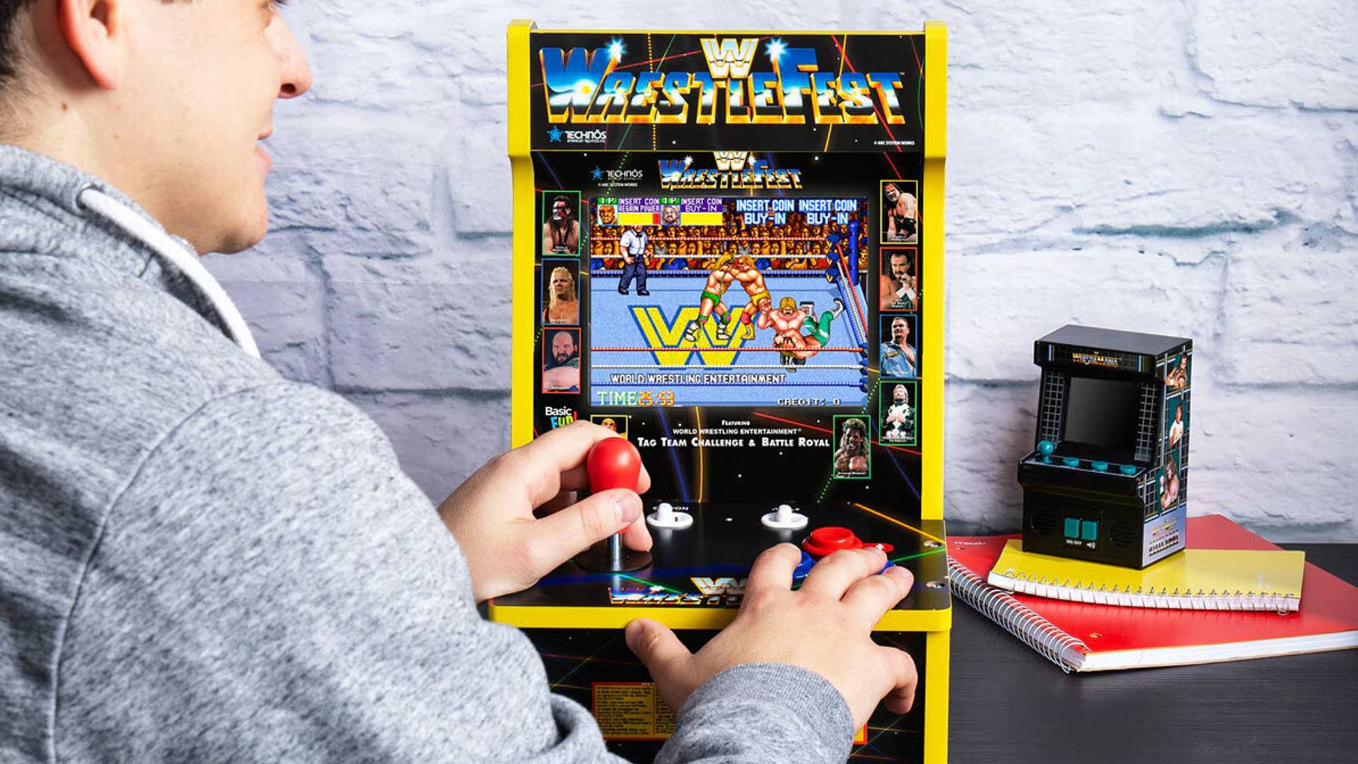 Masc person playing Arcade Classics WWE arcade machine on desk.