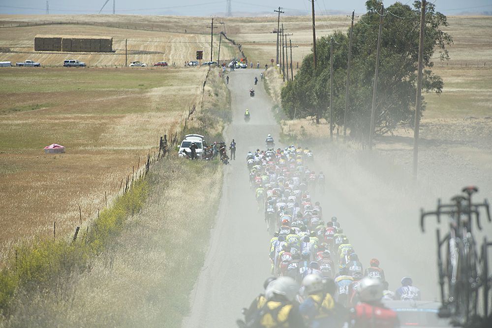The dust kicks up as the peloton races through the countryside outside of Sacramento