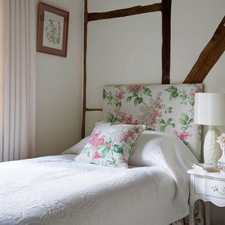 bedroom with white walls and bed with floral printed pillows