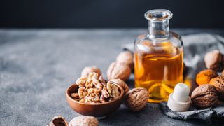 walnut oil in glass bottle with small bowl of walnuts