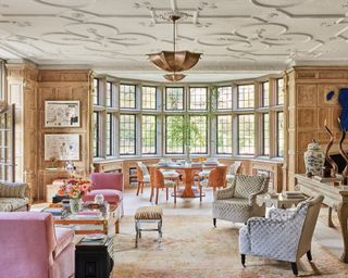 Spacious living room with armchairs, dining table and chairs, chandelier and ornate ceiling