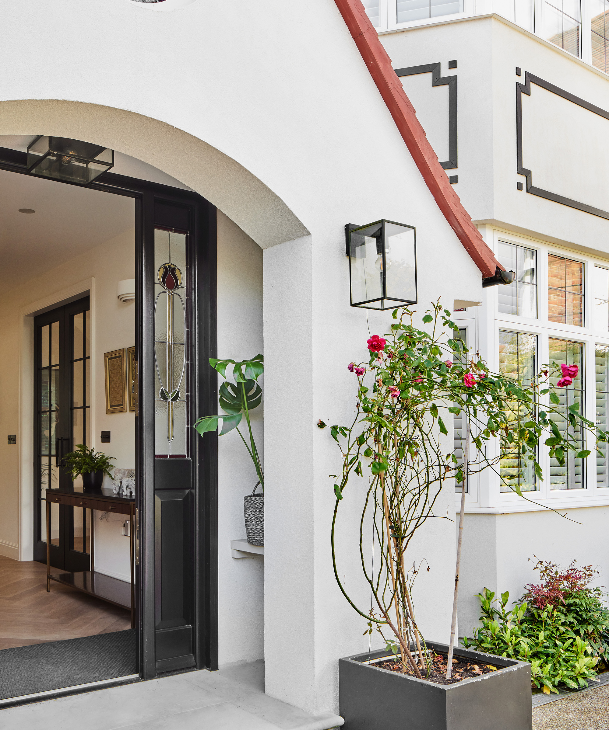 View of a front door with a porch and large potted rose plant