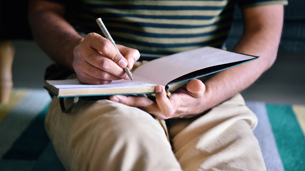 A man writing in a book.