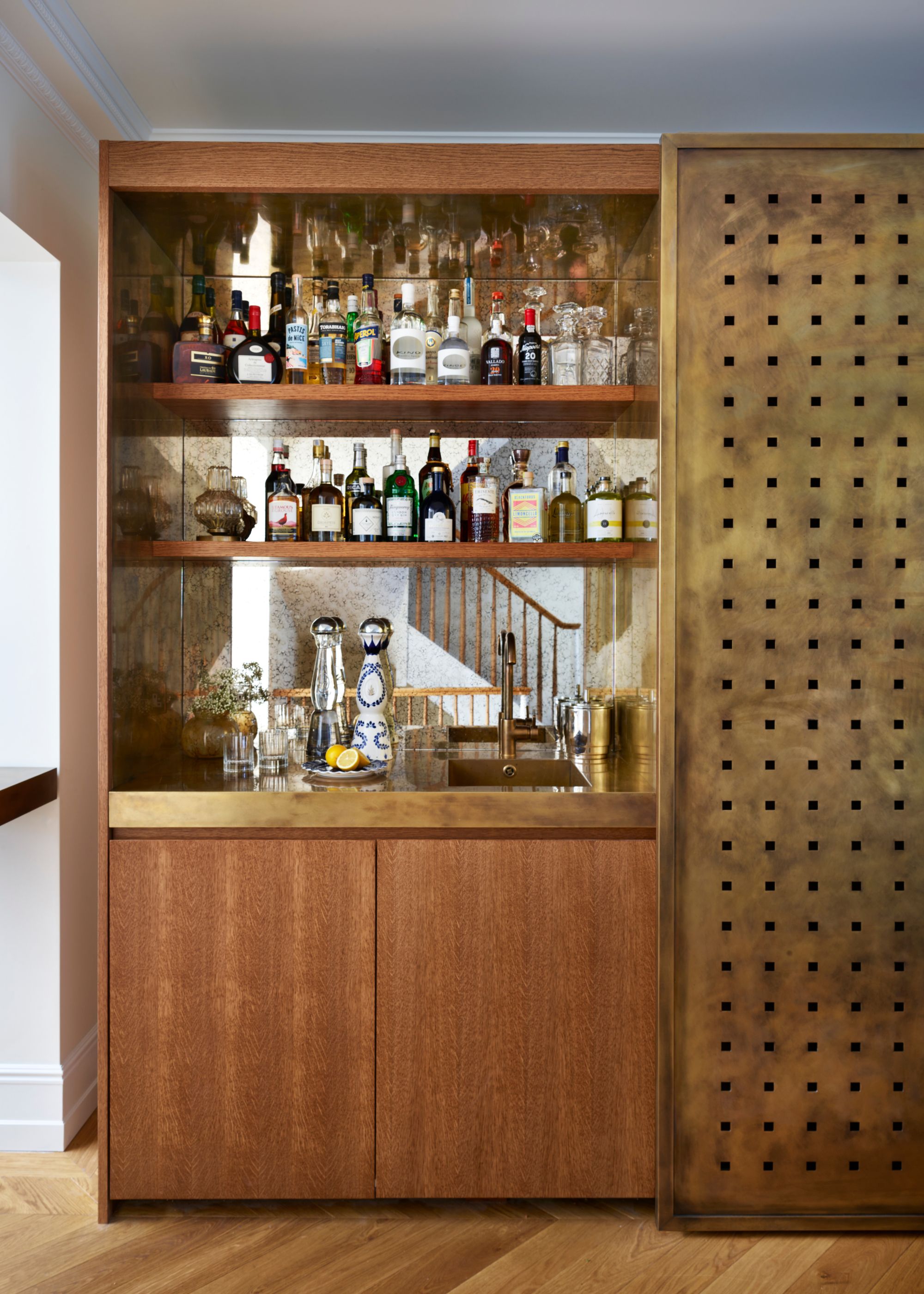 home bar with wooden front and brass panel, antiqued glass on the back wall