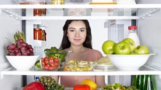 Woman looking at healthy snacks in fridge