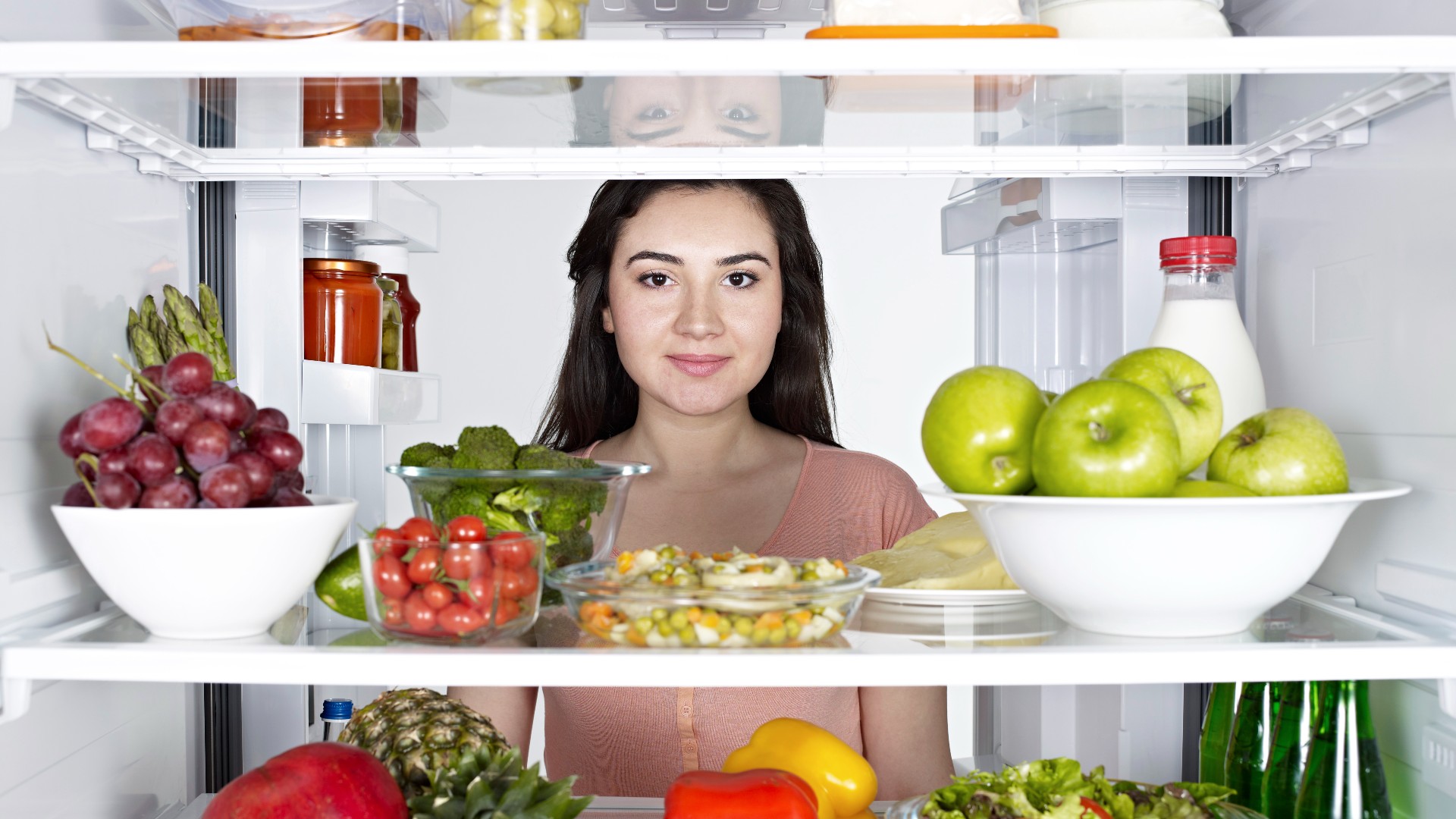 Woman looking at healthy snacks in the fridge