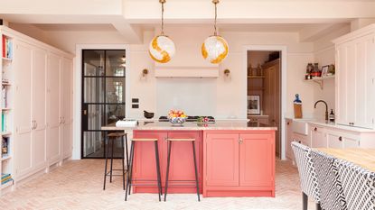 Shaker kitchen with large coral kitchen island and two large globe pendant lights above