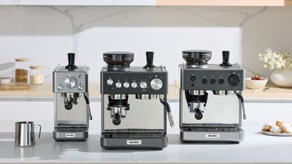 Image of a white kitchen with white marble backsplash and three of the Breville Barista Sense Espresso Machine's sitting on the counter.