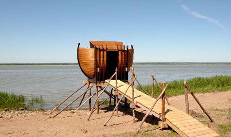 Wooden boat on stilts being constructed on a river bank