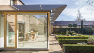Large glass and timber single storey extension on rear of property with metal detailing on roof that extends over the extension