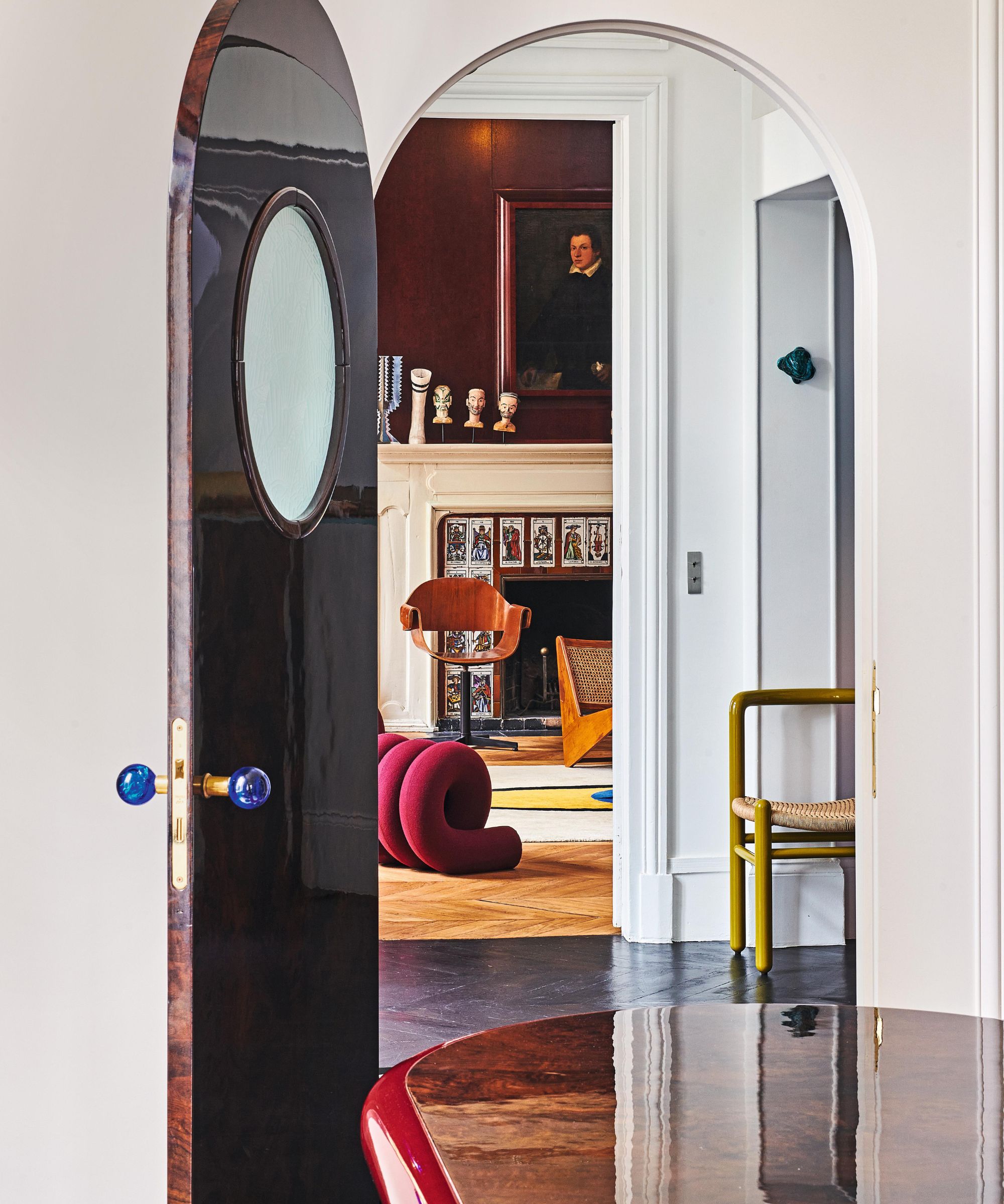 an arched doorway looking through to a moody eclectic Parisian sitting room