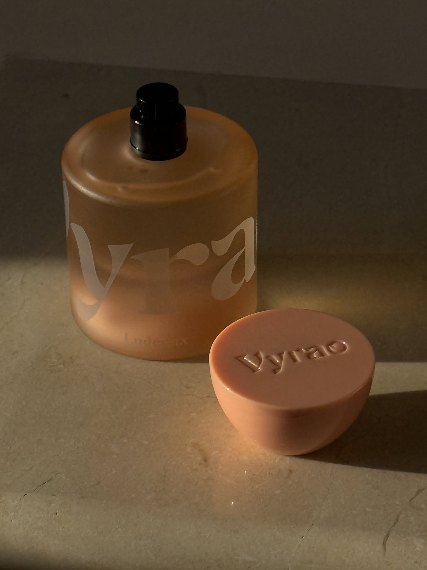 A pink Vyrao perfume on a stone table