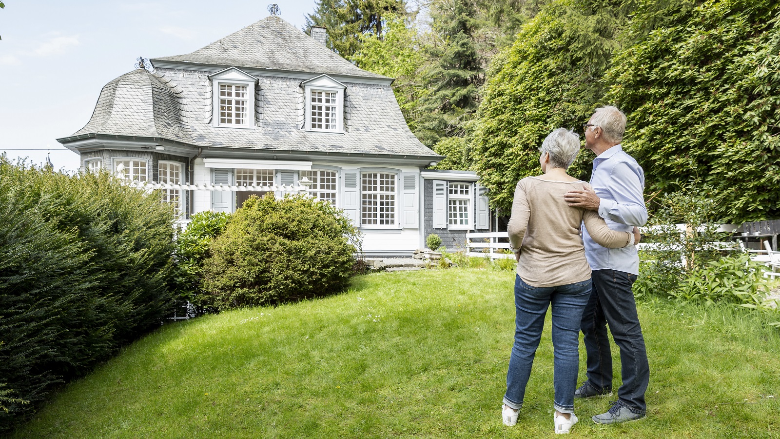 A senior couple stand outside their inherited house.