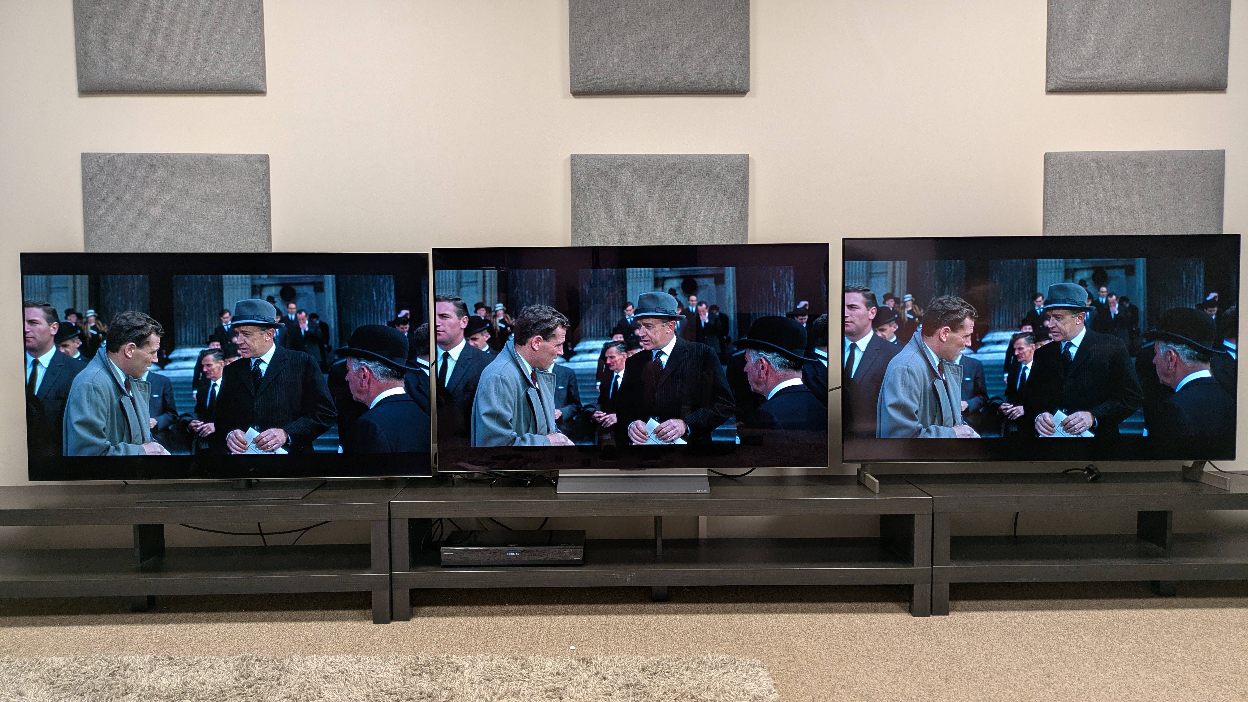 LG G6 (left) vs LG C6 (middle) vs LG B6E (right) showing a group of people outside a funeral from Lawrence of Arabia. The G6 and B6E have green tints that affect skin tones, while the C6 is accurate.