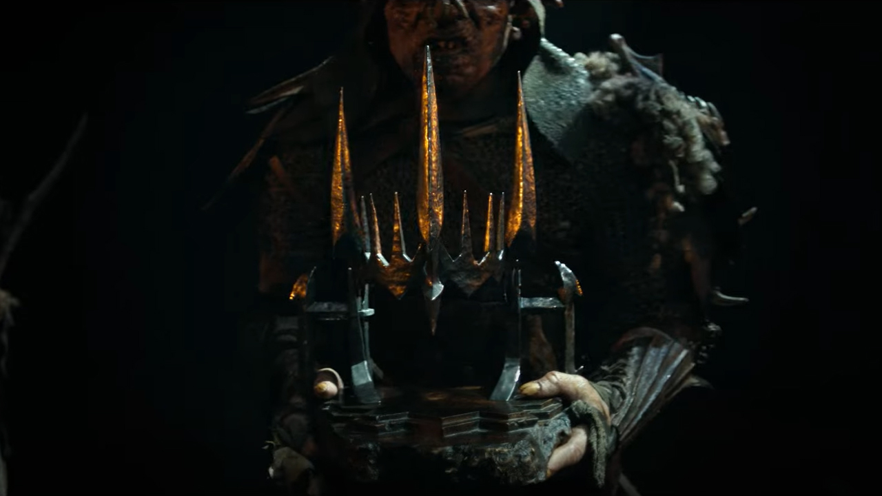 An orc carries a helmet or crown in a dark cave in  in The Rings of Power season 2
