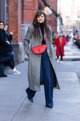 katie holmes wearing a grey coat, jeans, boots, and a black turtleneck,