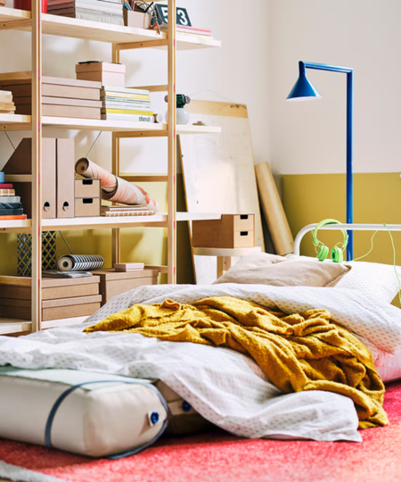 a room with products from IKEA's PS collection including the chair bed the twisting lamp, and the open shelving unit