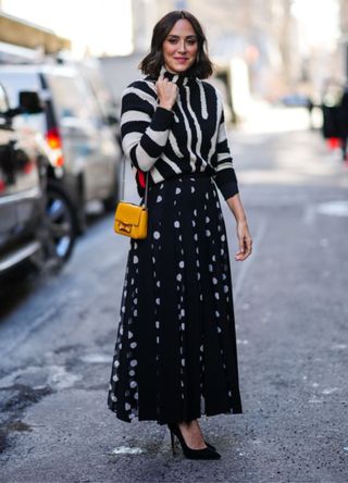 A guest wearing a black and white zebra print pattern turtleneck and a yellow shiny leather shoulder bag from Carolina Herrera.