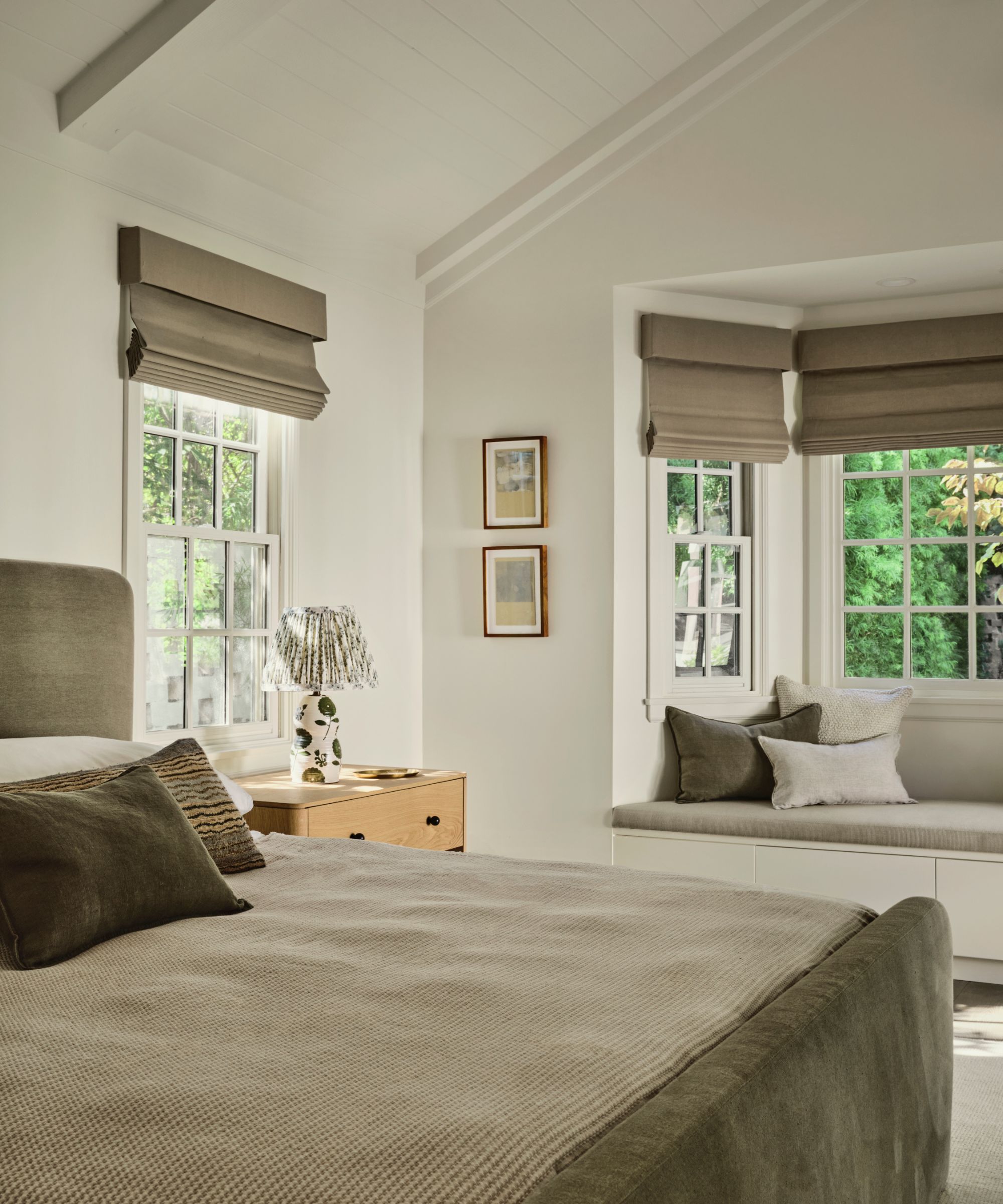 calming bedroom with white walls, sloped ceiling, and taupe bedding and window blinds
