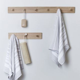 white wall with wooden peg rail and throws