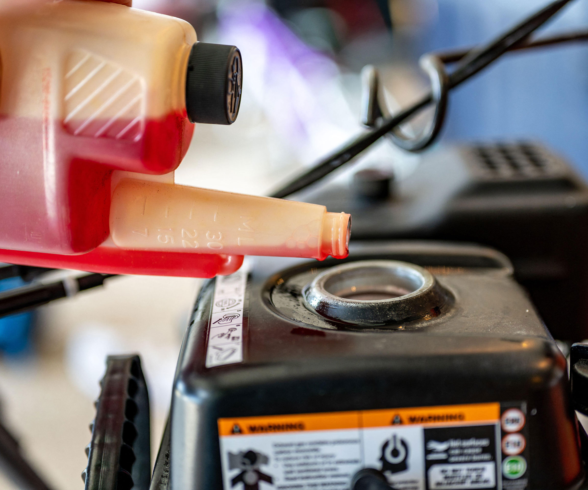 red stabilizer fluid being poured into a lawn mower