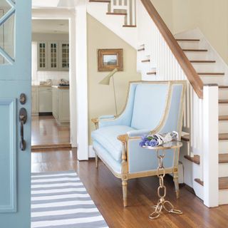 hallway with blue chair and wooden floors, striped rug