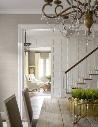 Hallway with chandelier seen from dining room with staircase with panelled walls