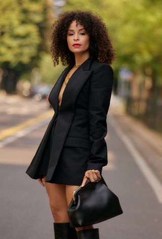 a photo of a woman wearing a black blazer dress and fendi clutch bag