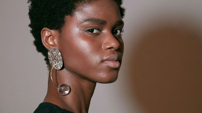 A model backstage with glowing skin to depict the debate for how to use foundation and BB cream together