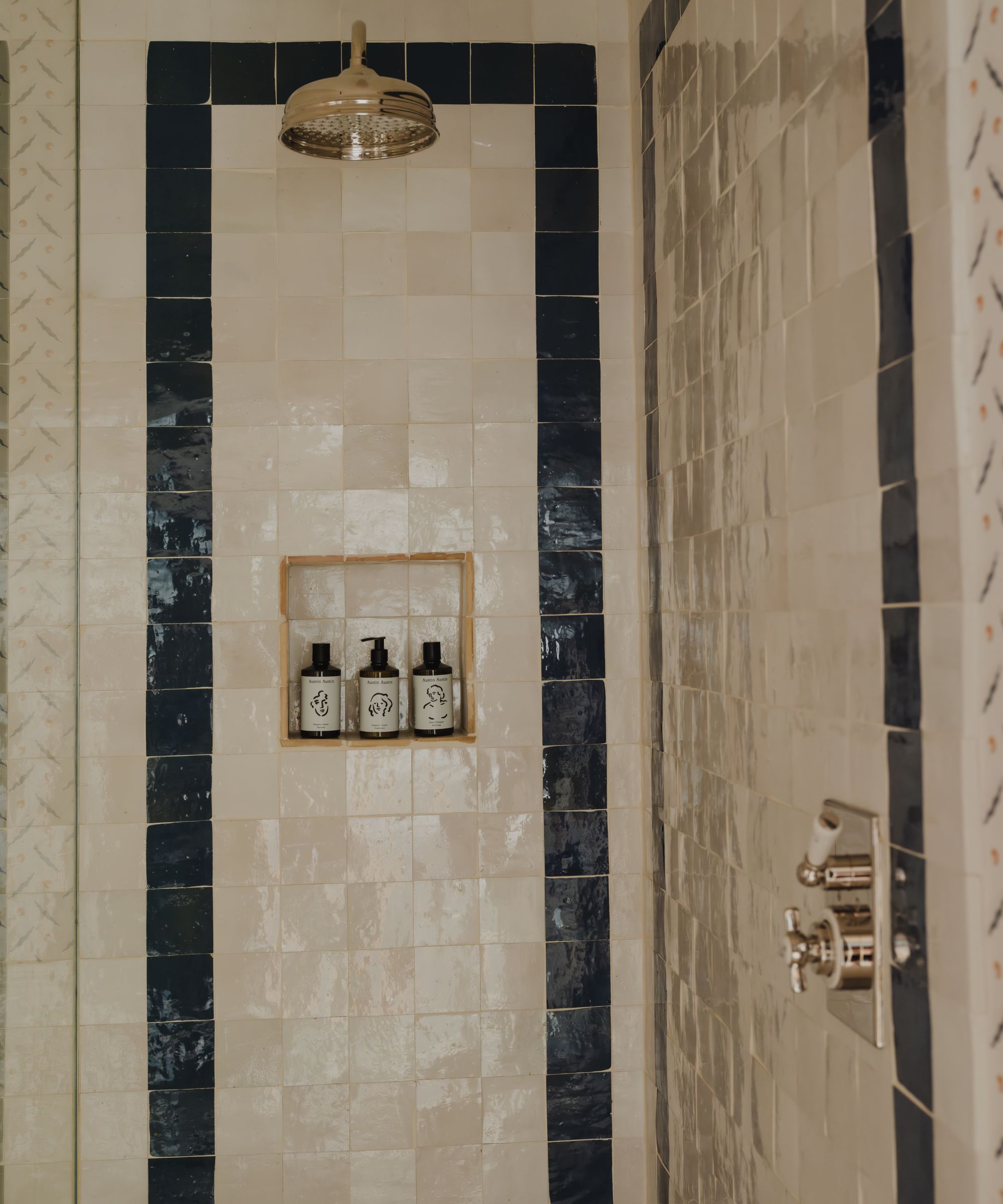 a shower enclosure with neutral and navy blue zellige tiles
