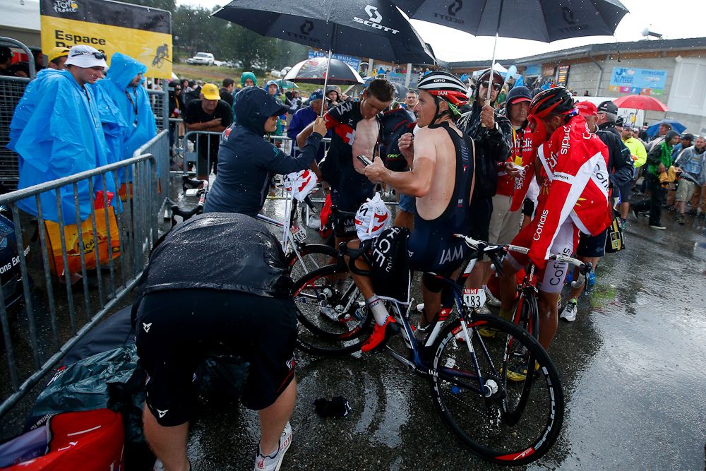 Riders seek relief from the rain after finishing stage 12.