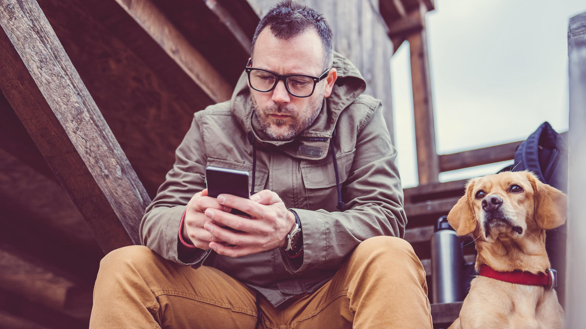 Man glued to his phone, dog sitting beside him
