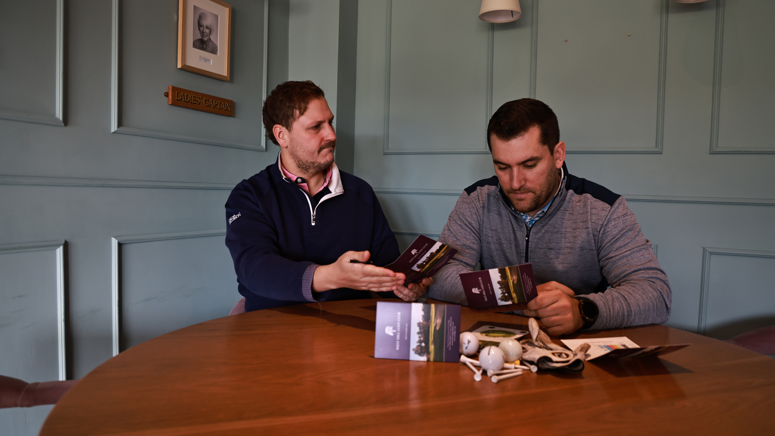 Nick Bonfield and Sam De'Ath examining their respective scorecards in the clubhouse