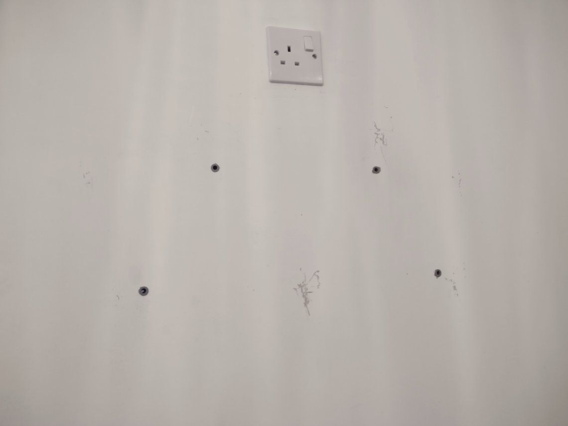 Holes in a white kitchen wall ready for screws