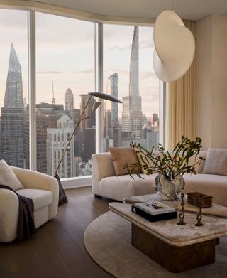 A low-profile couch and armchair set before a window overlooking Manhattan's skyline