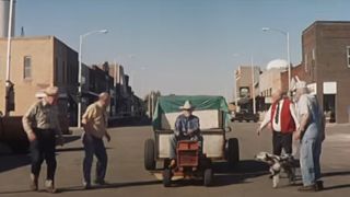 Richard Farnsworth driving a tractor amidst people in The Straight Story