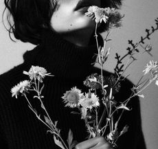A woman in the shadows holding a bunch of wild flowers