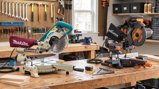 Two of the best mitre saws on a work bench in a garage