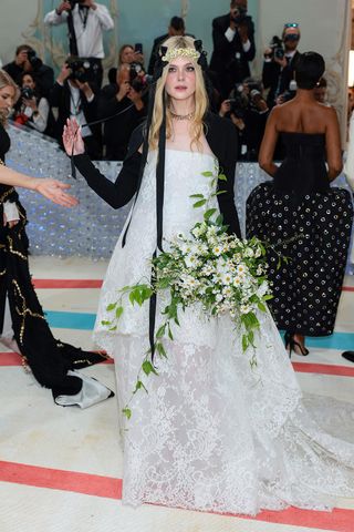 Elle Fanning opts for etheral chic in white and black accessorised with fresh flowerson the Met Gala red carpet 2023