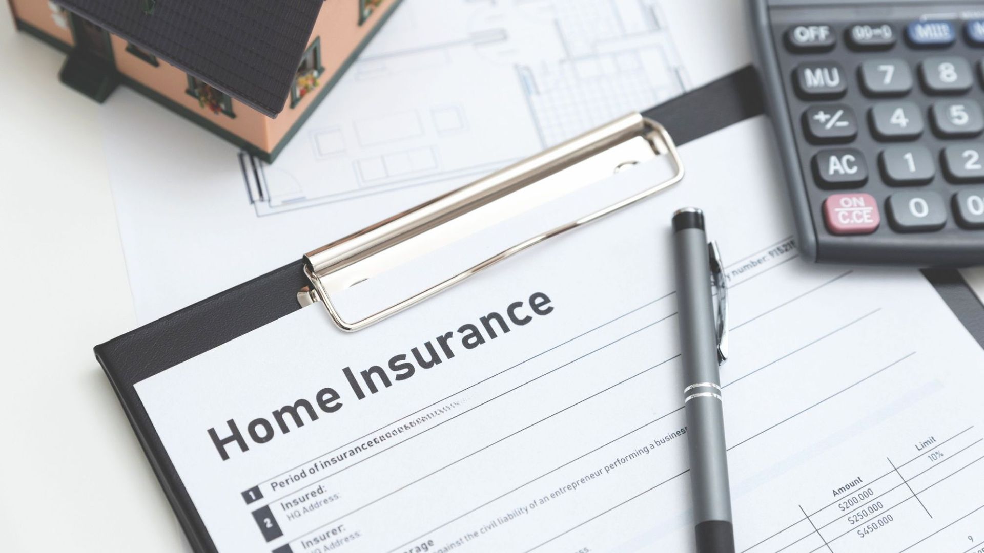 A home insurance document lying on a desk next to a calculator