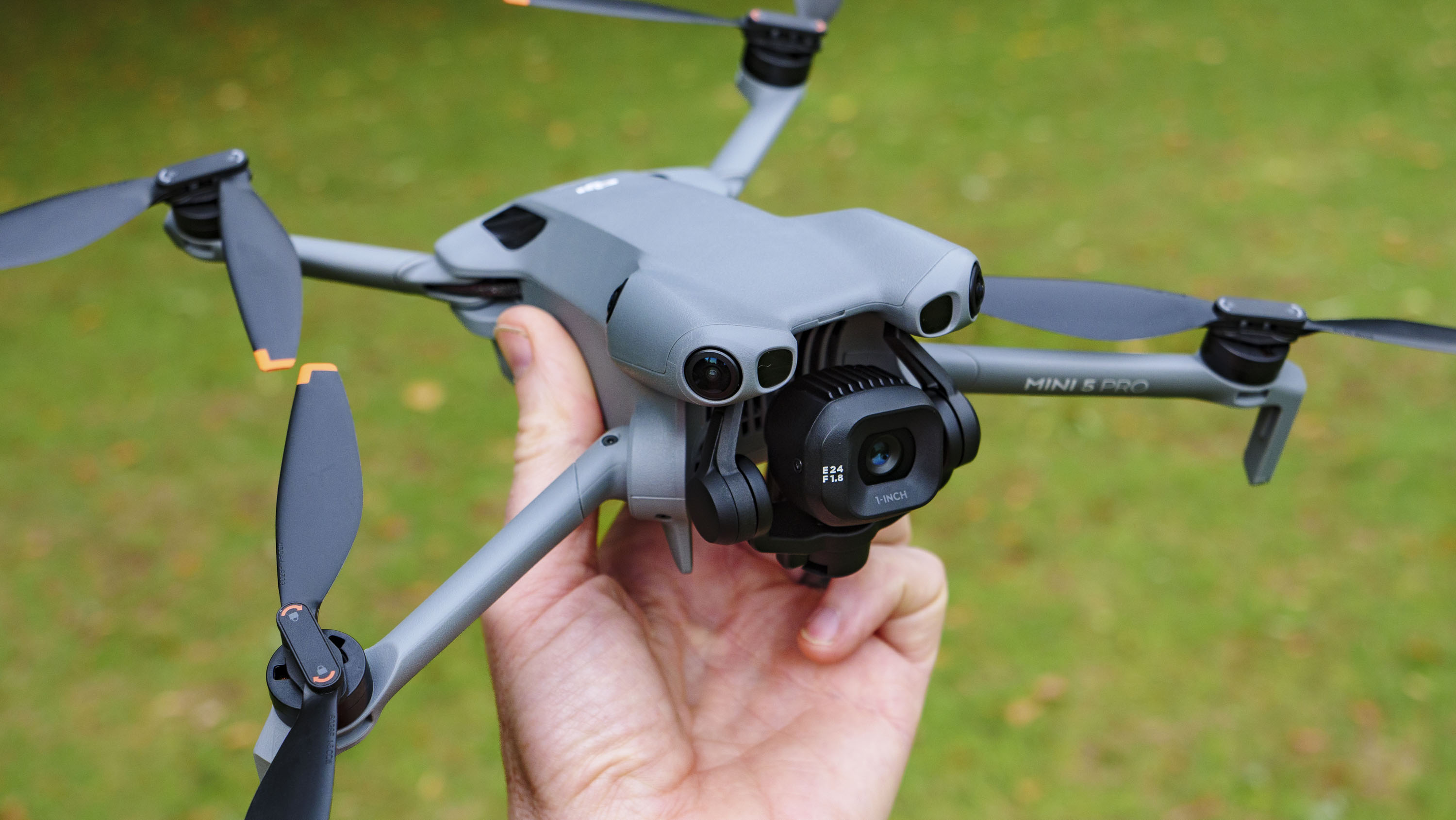 DJI Mini 5 Pro in pilot&#039;s hand, grass background