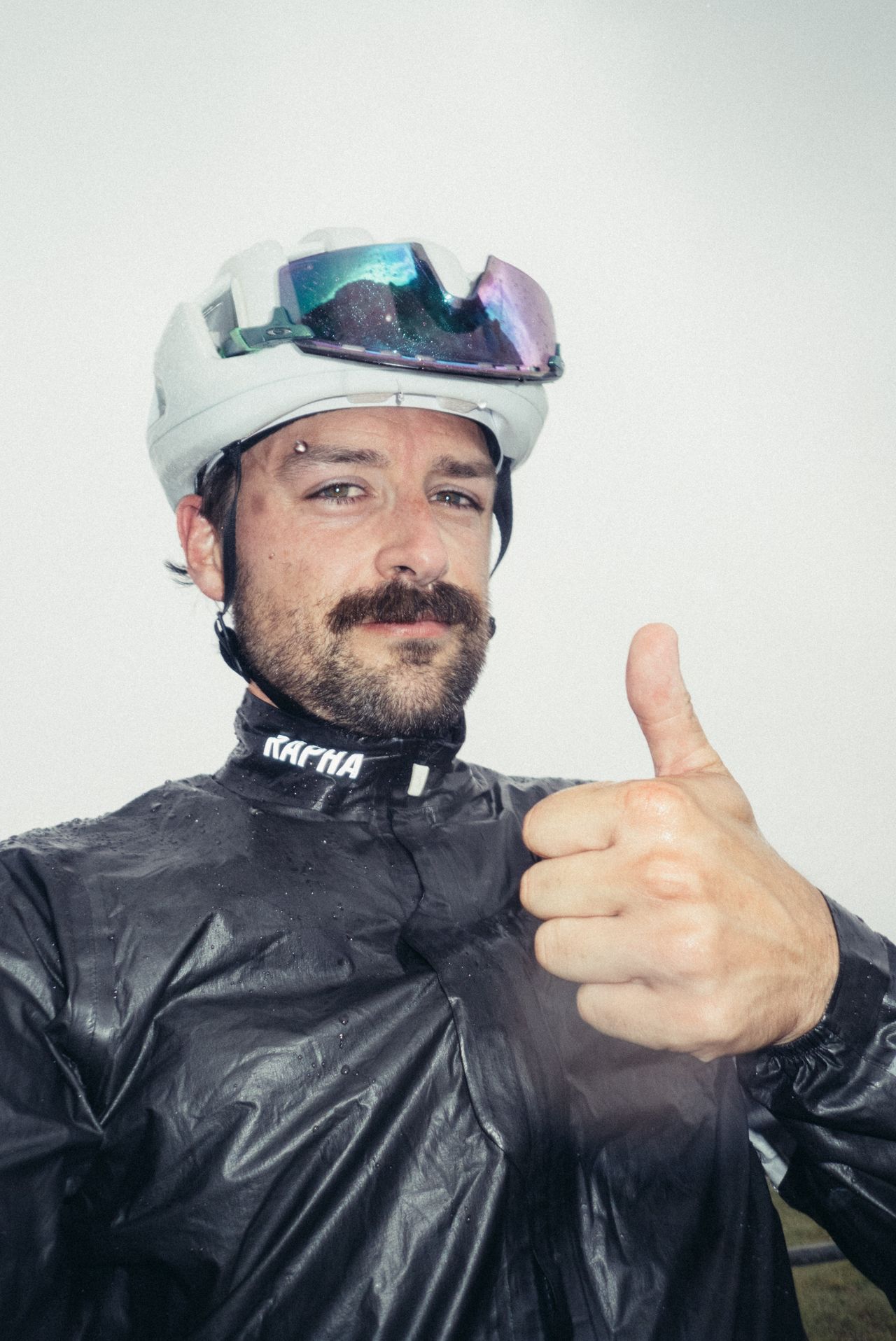 A man in a black cycling jacket gives a thumbs up