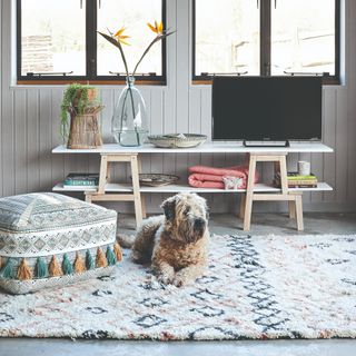 A living room with a f;uffy patterned rug and a Boho pouffe
